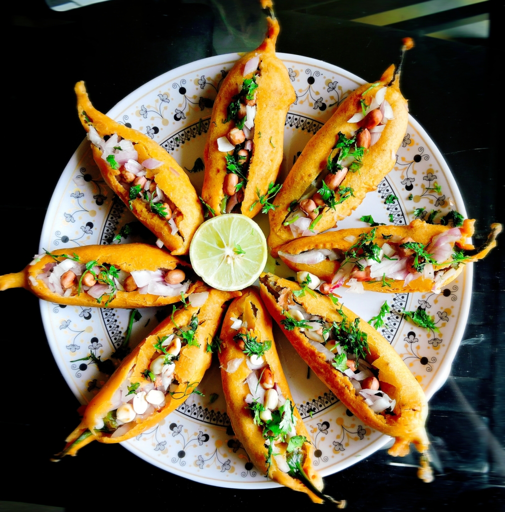 Mirapakaya Bajji is chilli stuffed with a tangy spice mix.Then it is dipped in besan batter and fried.Later the chilli is stuffed again with tangy onion filling. The combination of tangy onions and chillies is pure bliss.
